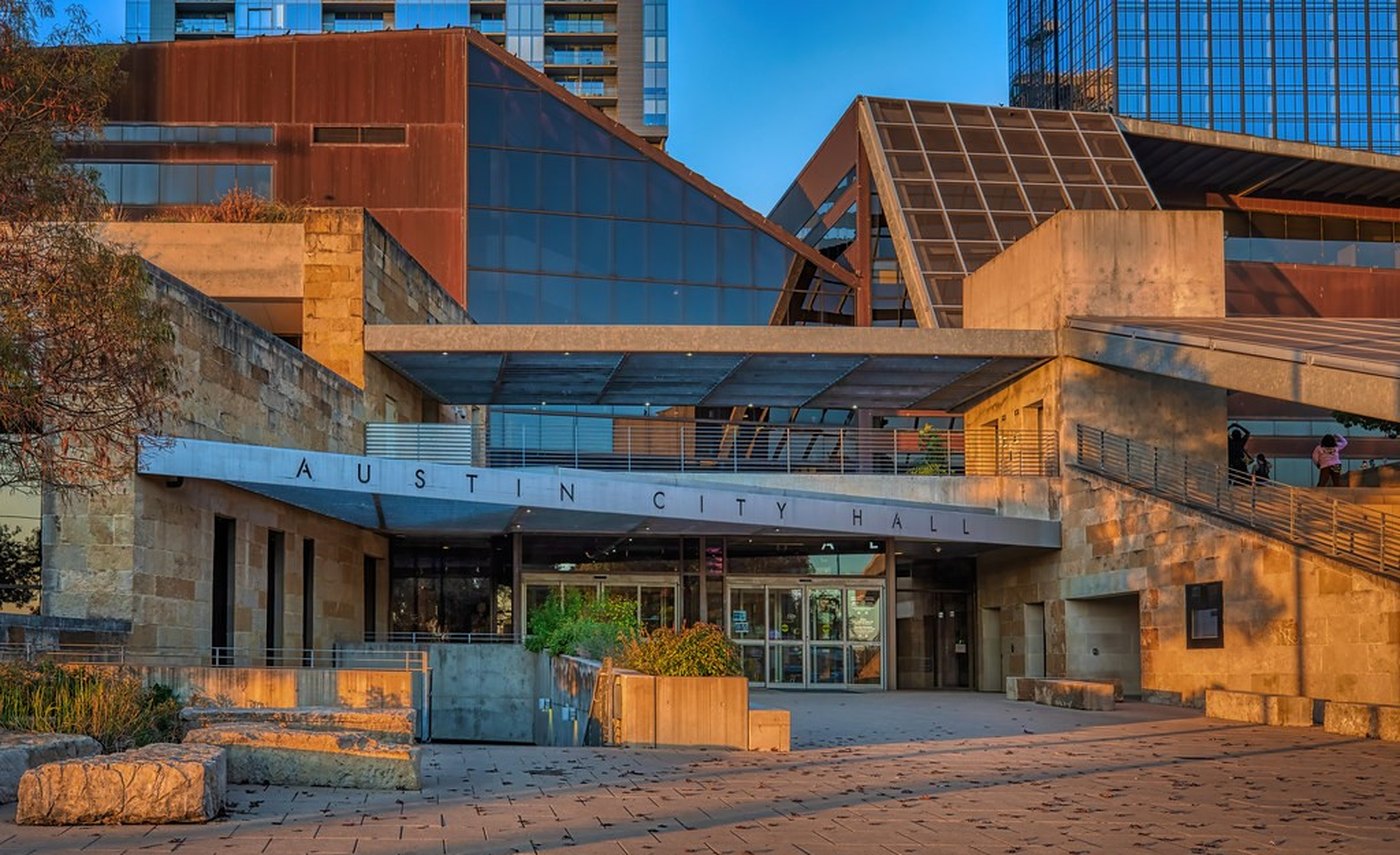 Austin City Hall at golden hour, its name cut into the stone facade above the main entrance.